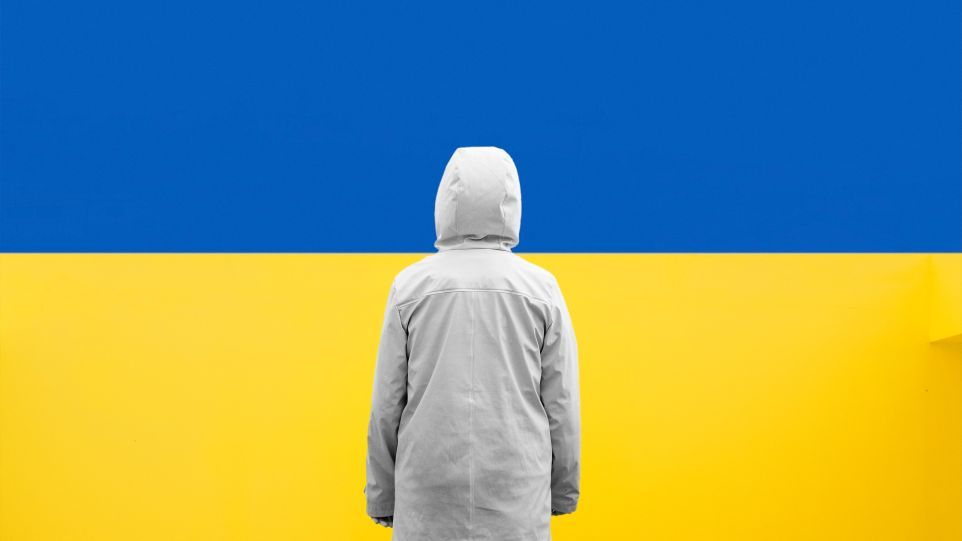 Person von hinten vor bildfüllender Ukraine-Flagge