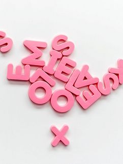 Verstreut herumliegende, pinke Buchstaben aus Plastik.
