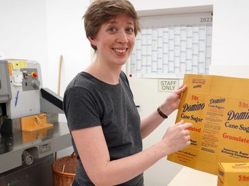 Mitarbeiterin des Deutschen Museums mit einem Domino Cane-Sugar-Karton in der Hand