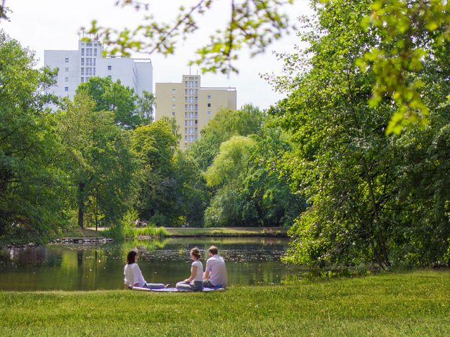 Drei Menschen sitzen am See im Park. 