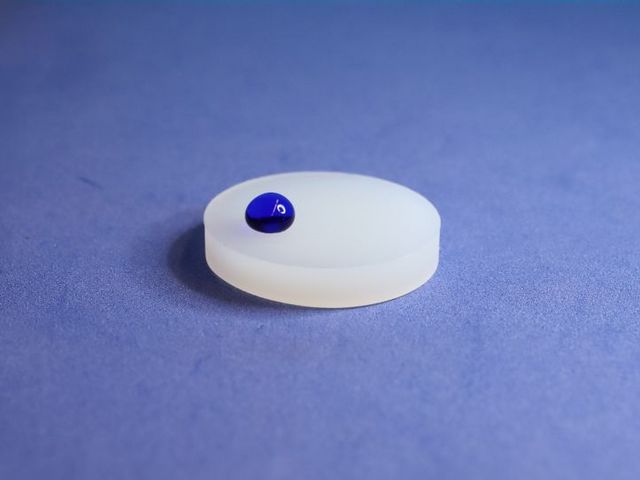 A plastic substrate has been treated with the new INP plasma process and is now water-repellent. A promising and environmentally friendly alternative to PFAS-based coatings. Plastic disc with blue drop