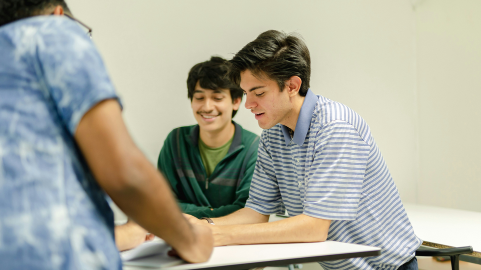 Drei Schüler sitzen an einem Tisch und unterhalten sich