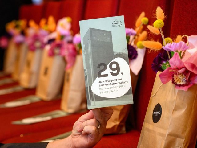 Flyer der Leibniz-Jahrestagung, im Hintergrund Blumensträuße
