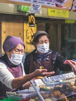 Zwei Japanische Händlerinnen auf einem Marktplatz. Beide tragen Maske