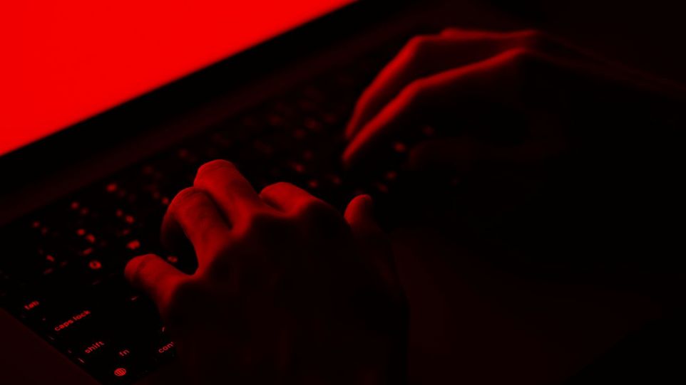 Hände auf Computertastatur mit roten Hintergrund