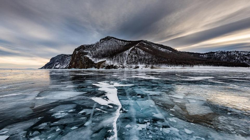 Zugefrorener See auf Island, im Hintergrund schneebedeckter Berg