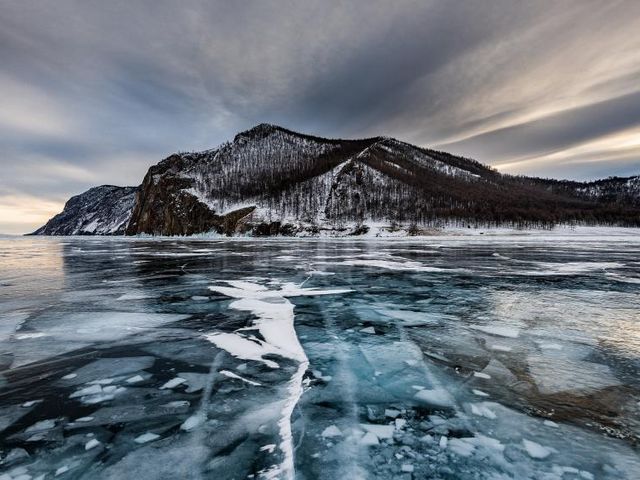 Zugefrorener See auf Island, im Hintergrund schneebedeckter Berg