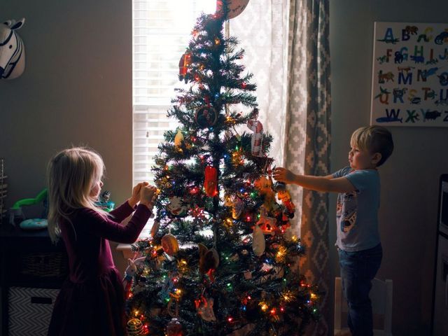 Zwei Kinder schmücken einen Weihnachtsbaum