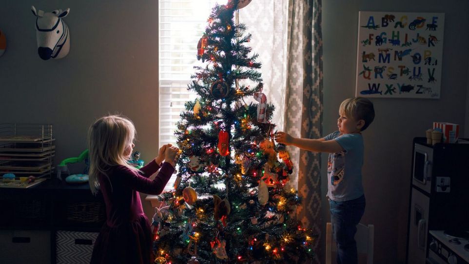 Zwei Kinder schmücken einen Weihnachtsbaum