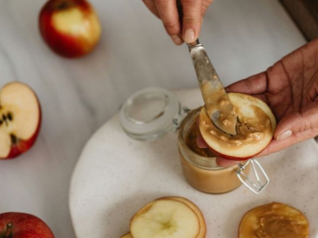 Aufgeschnittene Apfelscheiben werden mit Erdnussbutter bestrichen