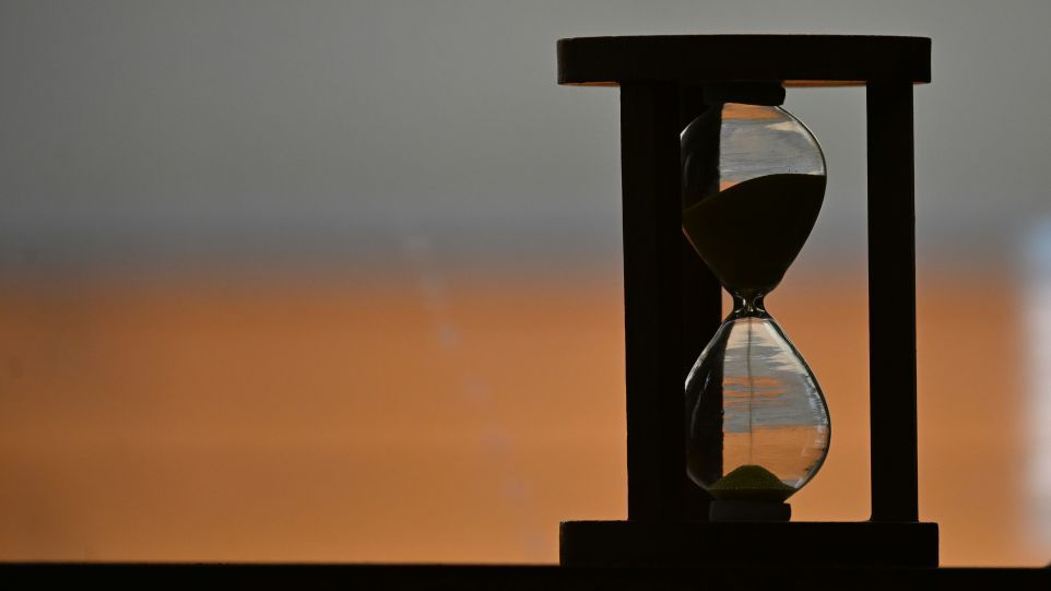 An hourglass against an orange-hued sunset
