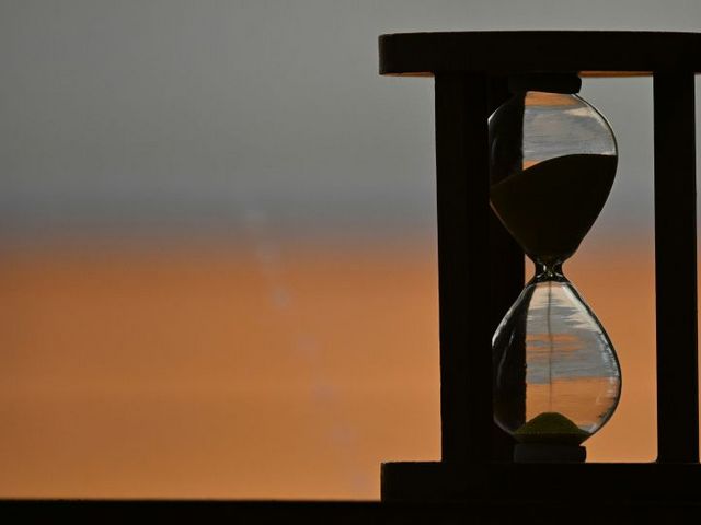 An hourglass against an orange-hued sunset