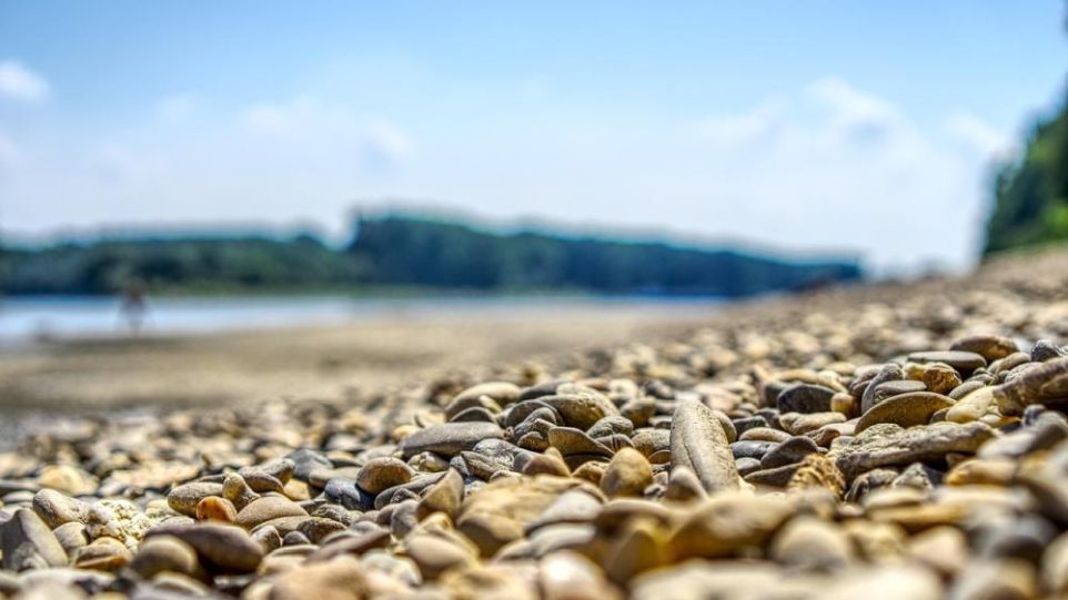 Durch den Ausbau von Wasserstraßen und Begradigungen wurden Flüsse in Deutschland um durchschnittlich 20 Prozent kürzer. In der Folge fließt das Wasser schneller ab; die Folgen des Klimawandels verschärfen sich. Kiesstrand an einem Flussufer