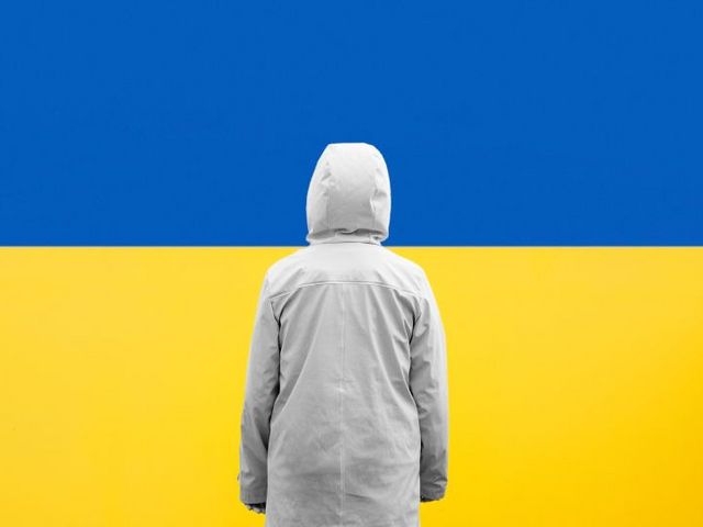 Person von hinten vor bildfüllender Ukraine-Flagge