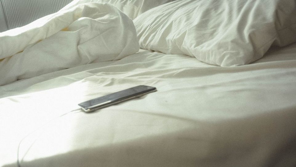 Smartphone in zerwühltem Bett