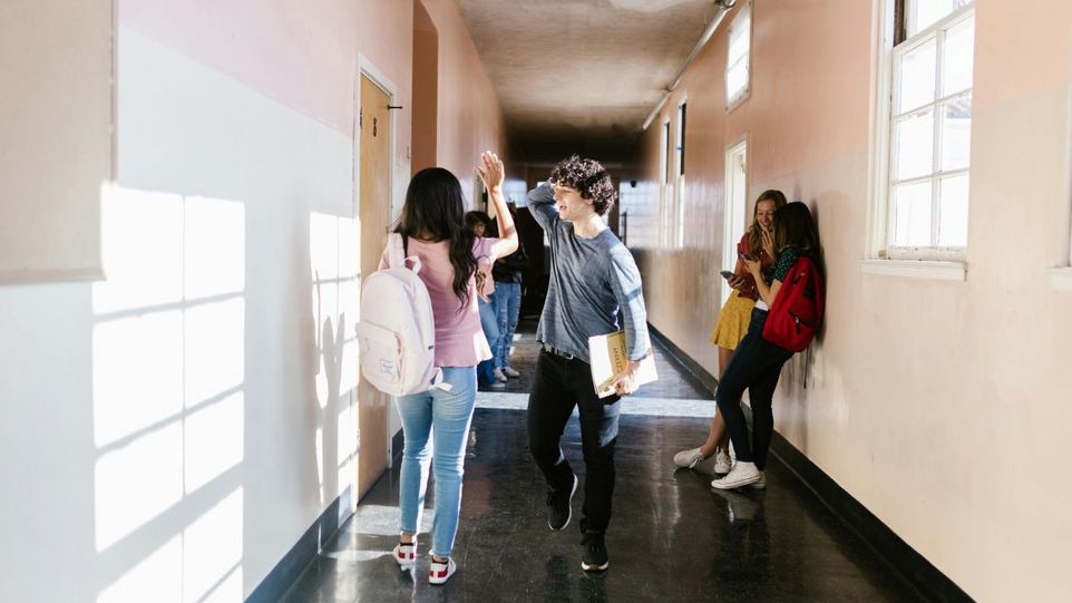 Schüler und Schülerin beim Highfive in einem Schulflur