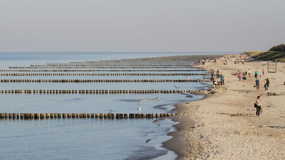 Gruppe von Menschen, die an einem Strand am Meer entlang spaziert