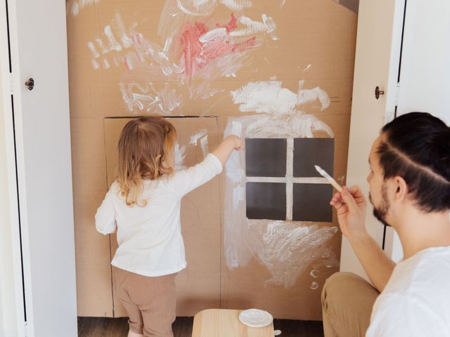 Mann streicht mit seinem Kind unsauber eine Wand