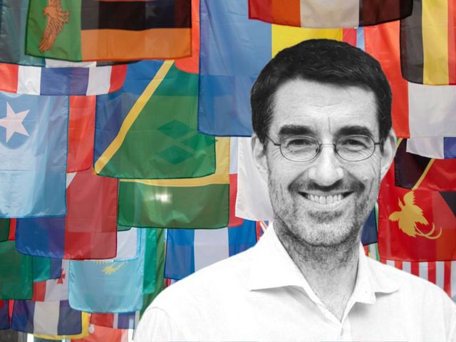 Portrait Tilman Brück, im Hintergrund internationale Fahnen