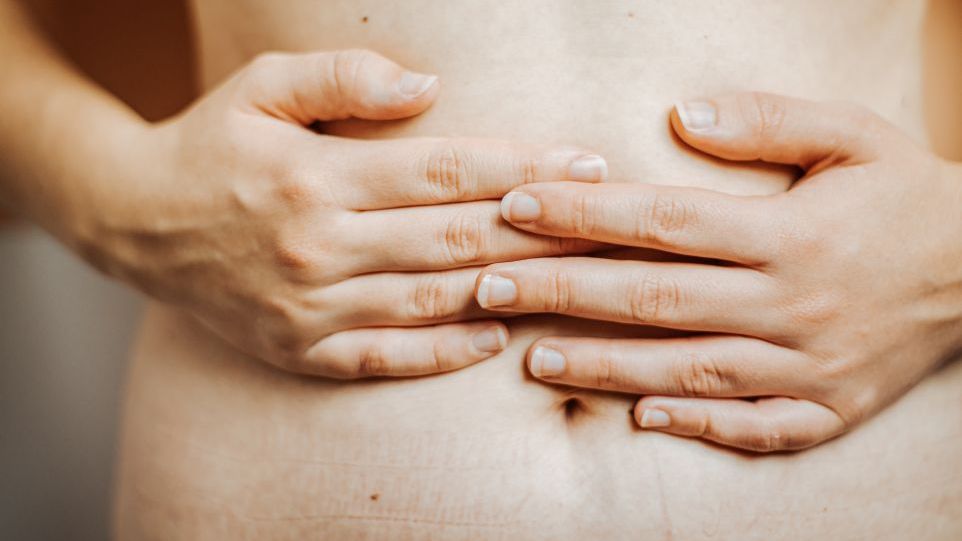 Hände, die auf dem Bauch liegen.