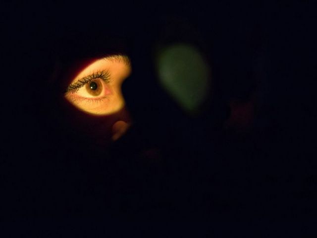 Gesicht im Dunkel, nur ein Auge wird angestrahlt