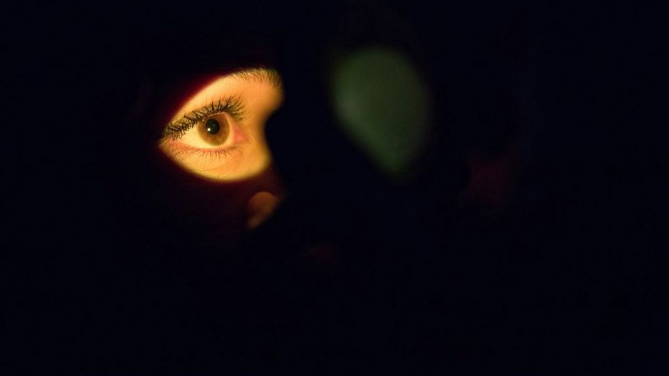 Gesicht im Dunkel, nur ein Auge wird angestrahlt