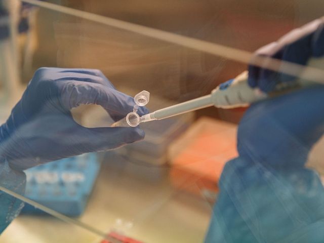 Hands pouring liquid into a glass using a pipette