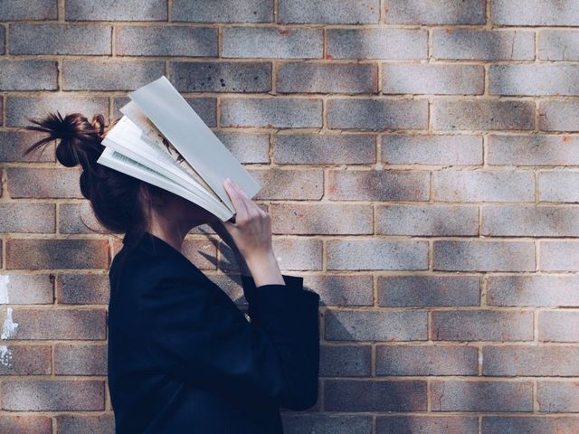 Young woman covering her face with an open book