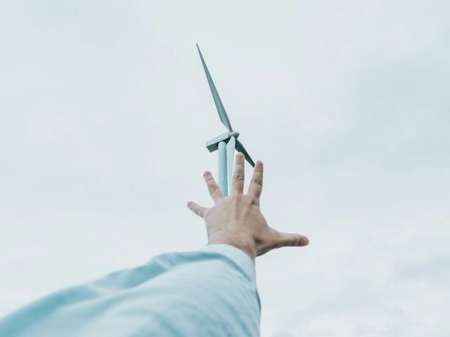 Hand reaches for wind turbine