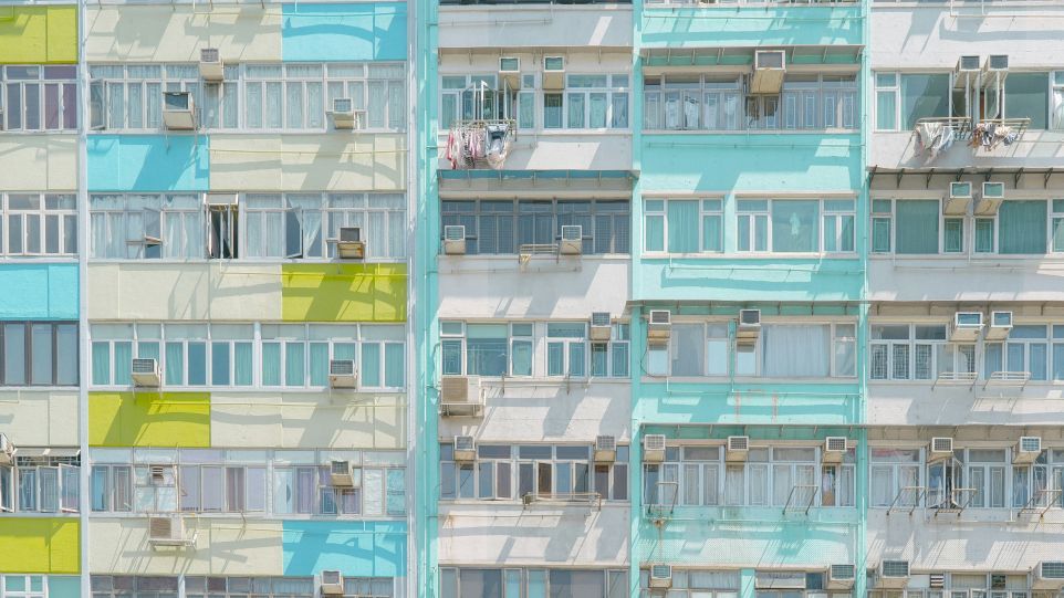 Fassade eines mehrstöckigen Wohngebäudes mit Fenstern, Balkonen und außen montierten Klimaanlagen