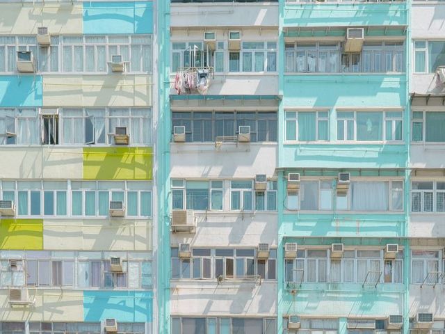 Fassade eines mehrstöckigen Wohngebäudes mit Fenstern, Balkonen und außen montierten Klimaanlagen