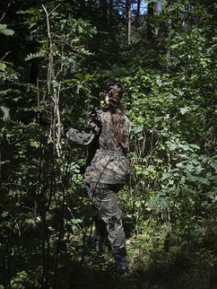 Eine uniformierte Frau geht in einen dichten Wald.