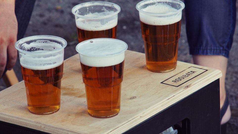 Vier mit Bier gefüllte Plastikbecher auf einem Tisch