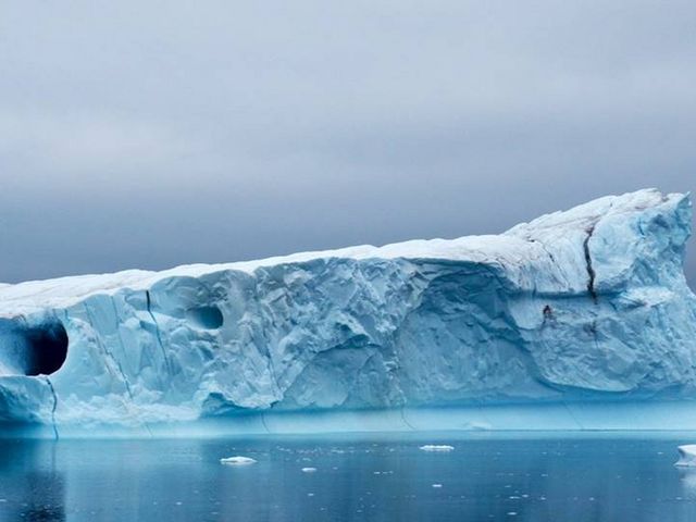 Iceberg in calm sea, water partly frozen