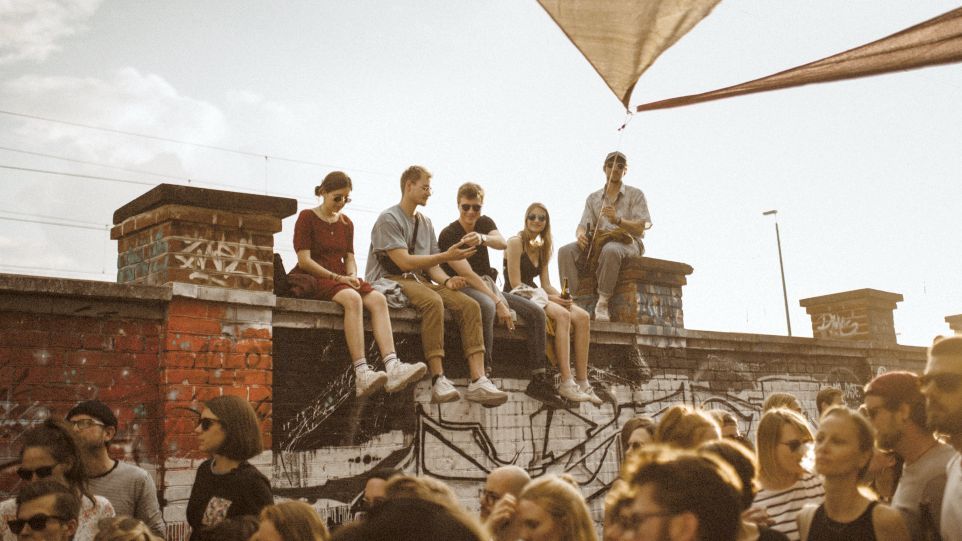 Junge Menschen sitzen auf einer Mauer in München