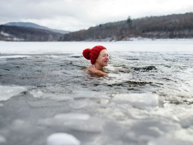Frau mit Pudelmütze in einem Eisloch
