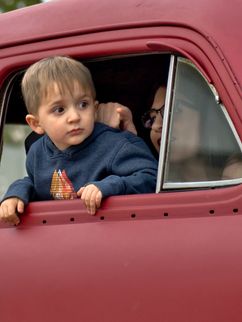 Junge am Fenster eines roten Autos.
