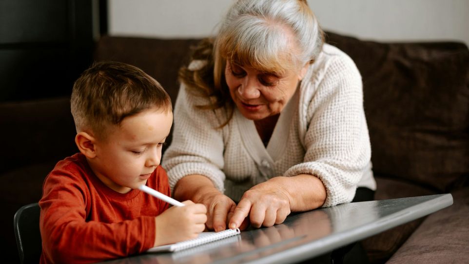 Ältere Frau unterstützt ein Kind beim Lernen