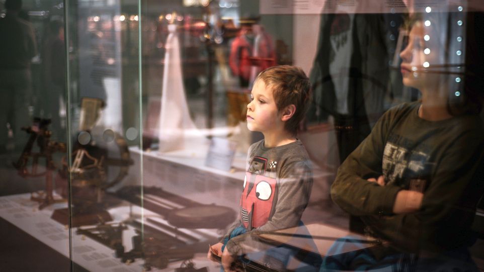 Zwei Jungen vor der Vitrine eines Museums mit alten Gegenständen