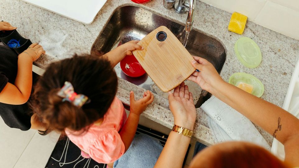 Zwei Kleinkinder lernen, ein Brettchen abzuspülen