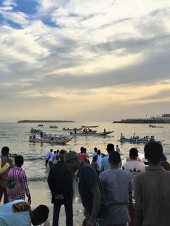 Zuschauer am Strand von Dakar beobachten ein Pirogenrennen, das in der Nähe des Fischmarkts der Stadt ausgetragen wird.