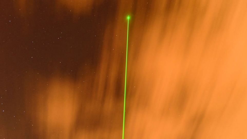MARTHA ("Multiwavelength Atmospheric Raman Lidar for Temperature, Humidity, and Aerosol Profiling") ist das größte und älteste Lidar am TROPOS in Leipzig. Grüner Laserstrahl vor orangem Hintergrund