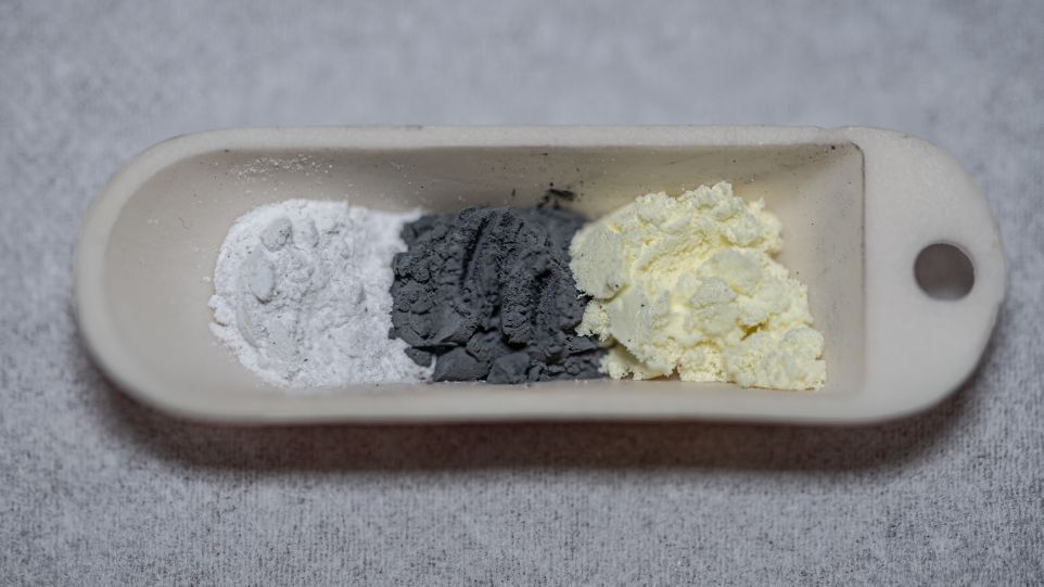 Kostengünstige und ungiftige Ausgangsstoffe nebeneinander geschichtet:  Lithiumoxid (weiß), Eisen (grau) und Schwefel (gelb) 
