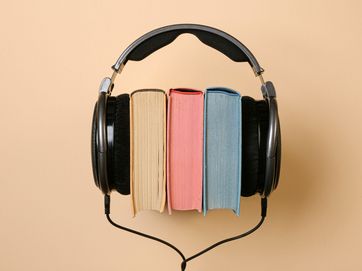 Von Kopfhörern umklammerter Bücherstapel