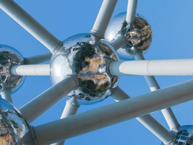 A view from below of the Atomium, with its gleaming metal spheres and white connecting tubes set against a blue sky
