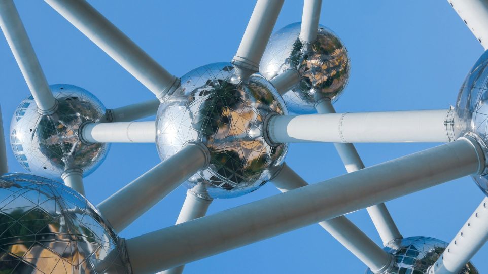 A view from below of the Atomium, with its gleaming metal spheres and white connecting tubes set against a blue sky