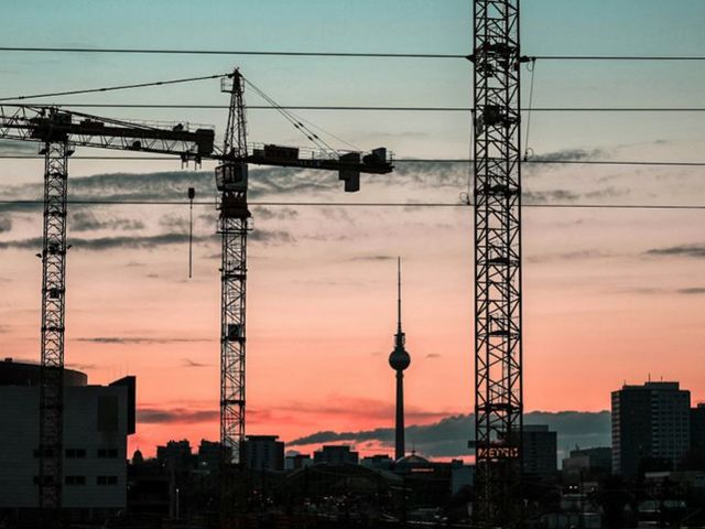 Berliner Skyline mit Fernsehturm und Baukränen in der Morgenröte