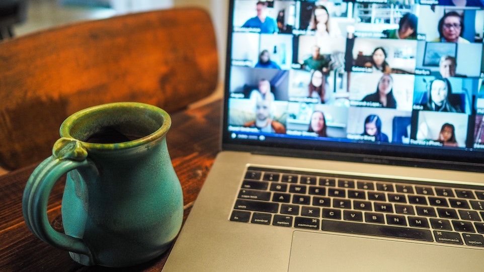 Tasse vor Laptop, auf welchem Videokonferenz läuft