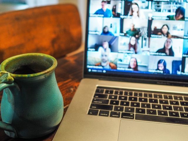 Tasse vor Laptop, auf welchem Videokonferenz läuft