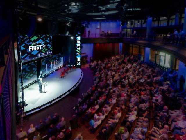 An event venue with an audience, a stage and a speaker